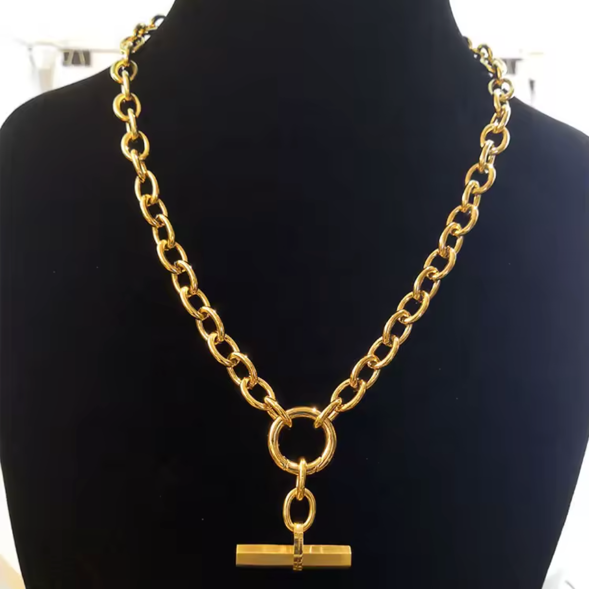 Gold chain necklace with a pendant on a black mannequin