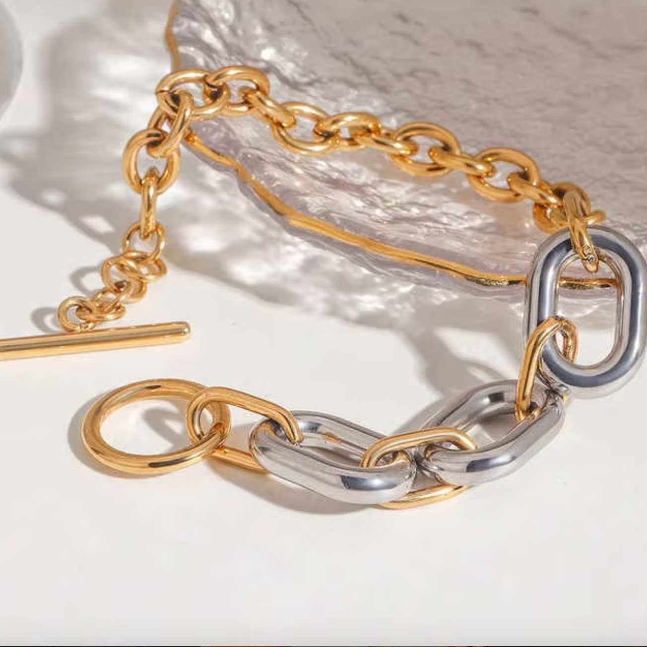 Gold and silver chain necklace on a light background