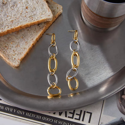 Gold and silver chain earrings on a metallic surface with toast and a cup.