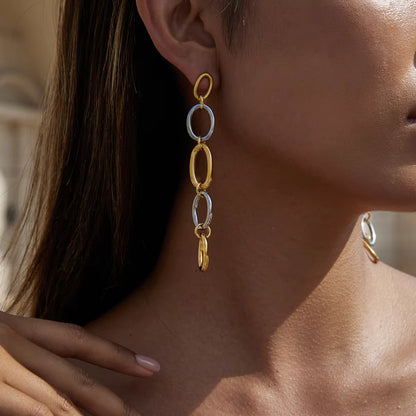 Close-up of a person wearing gold and silver chain earrings.