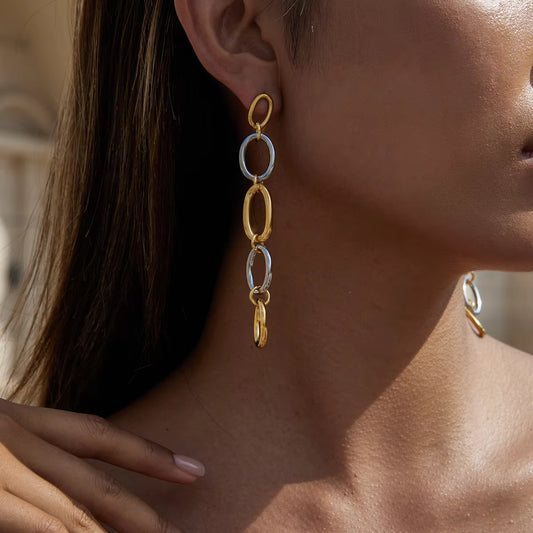 Close-up of a person wearing gold and silver chain earrings.