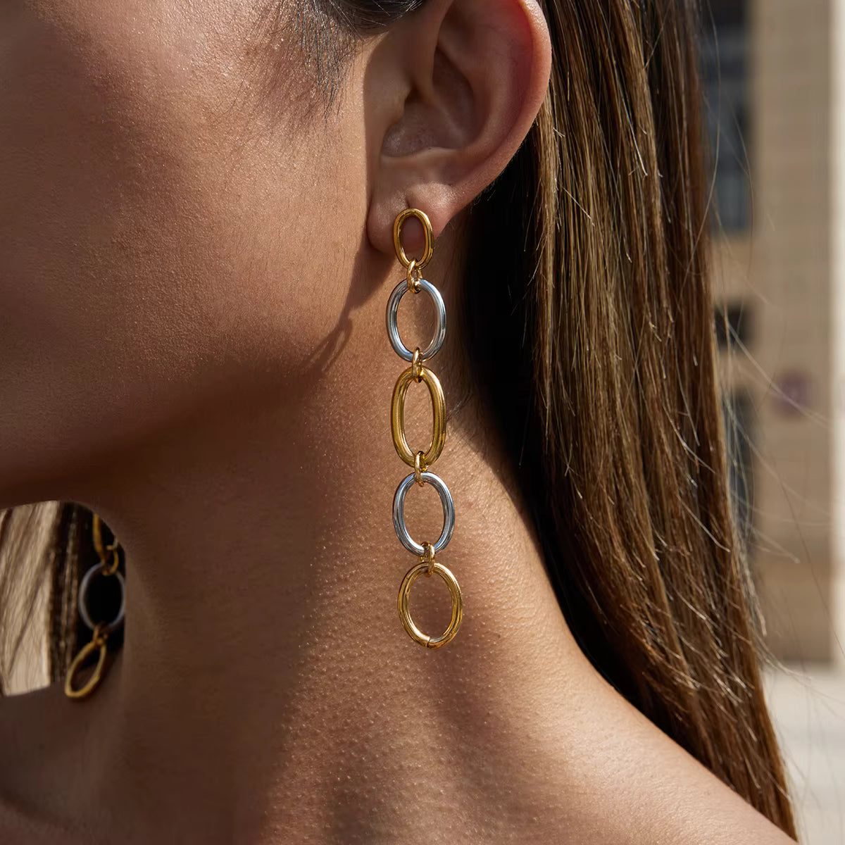 Close-up of a woman wearing gold and silver chain earrings.