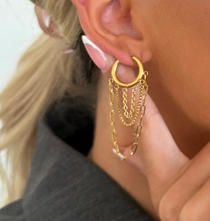 Gold hoop earring with chain details worn by a person