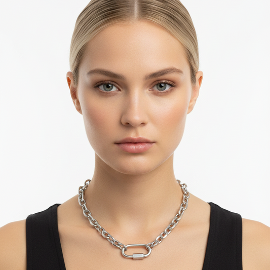 Woman wearing a silver chain necklace against a plain background