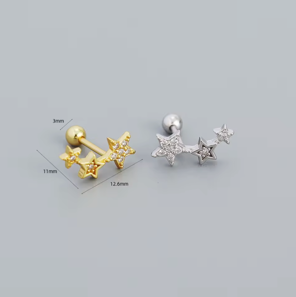 Gold and silver star-shaped earrings with measurements on a gray background