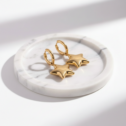 gold star-shaped earrings on a marble surface